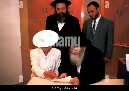 Un couple juif signer des documents avant d'un rabbin à leur mariage dans une synagogue à Jérusalem, Israël Banque D'Images