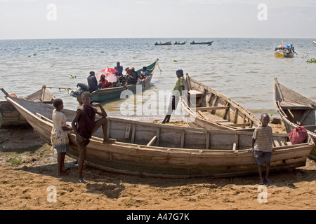 Scène au bord de bateaux de pêche et de ferry-boat, les garçons jouant par l'eau sur les rives du lac Albert, dans le Nord de l'Ouganda, Afrique E Banque D'Images