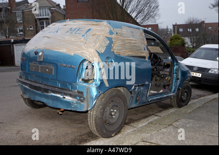 Vauxhall bleu abandonné et vandalisé des pièces de voiture accidentée à gauche sur la banlieue de Londres avec l'élimination de la rue Conseil d'avertissement Banque D'Images