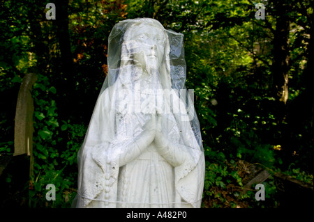 Statue d'une Vierge Marie prier dans le Cimetière de Highgate, couverte de feuilles de plastique contre les dommages et l'érosion du temps Banque D'Images