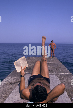 A Man reading et bronzer au bord de la mer de la mer Noire à Yalta Banque D'Images