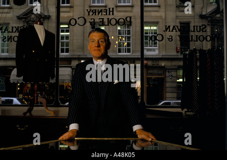 Dans un tailleur veste de costume debout à côté d'une vitrine de magasin sur saville row london Banque D'Images