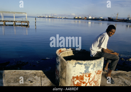 Jeune homme assis sur le quai à Port-au-Prince, Haïti Banque D'Images