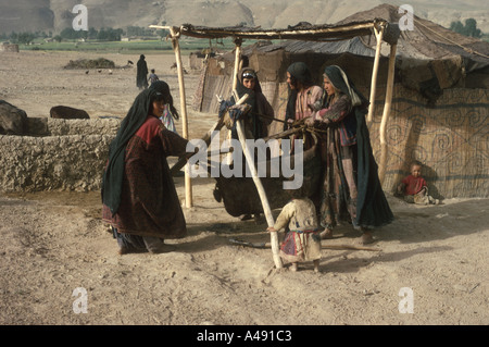 Firuskohi femmes nomades beurre churn dans un bullskin Chackcharan Chaqcharan près de l'itinéraire par centrale Afghanistan Minaret de Djam Banque D'Images