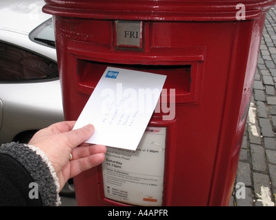Poster une lettre en un Royal Mail post box, UK. Banque D'Images
