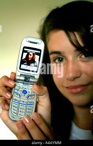 Une fille de l'adolescence de télécharger une vidéo de musique sur un mobile compatible 3G ou un téléphone cellulaire Banque D'Images