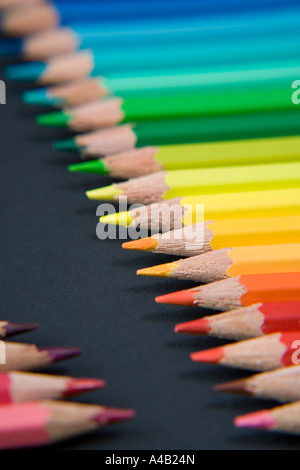 Crayons de couleur disposés en rangées sur un fond noir Banque D'Images