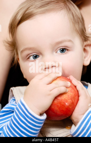 Mignon petit garçon mangeant une pomme rouge saine alimentation Santé de l'enfant vitamines face portrait Banque D'Images