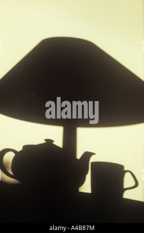 Ombre sur mur crème dans une lumière chaude de théière avec tasse et une lampe de table Banque D'Images