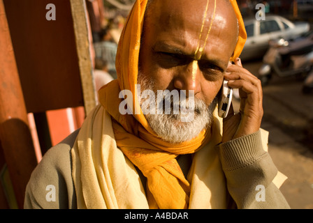 Image de prêtre hindou un brahmane en jaune robes de parler sur son téléphone cellulaire ou mobile Banque D'Images