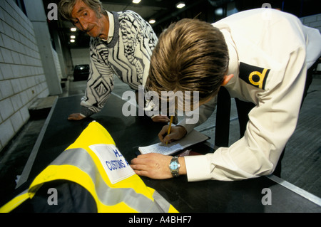 Un AGENT DES DOUANES ET ACCISE, port de Douvres SUR LA CÔTE SUD DE L'ANGLETERRE on confisque les biens des catalogues d'un passeur. Banque D'Images