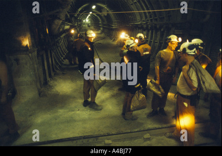 Mineurs DE DISCUTER AVEC HEADTORCHES DANS LE TUNNEL SOUTERRAIN, transportant des sacs de papier, Banque D'Images