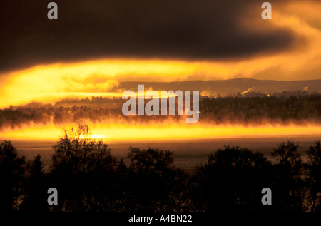 Suède : les feux du soleil d'hiver sombres nuages et brouillard d'or sur le côté du comté d'Ostersund Banque D'Images