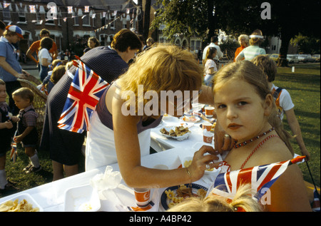 WOMAN FIXING HAUT DE JEUNE FILLE, À PARTIE POUR LE MARIAGE ROYAL 1981, RUE DE PENGE, LONDRES, ANGLETERRE Banque D'Images