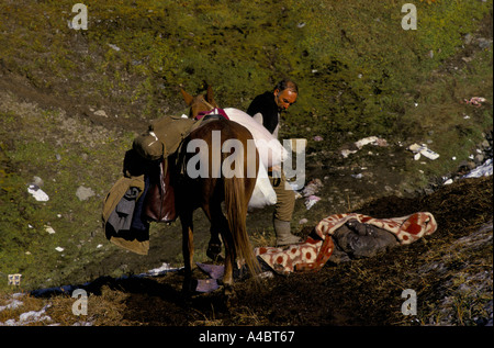 Col CHUBERI, GÉORGIE, octobre 1993 : son cheval lourdement chargé, un homme passe devant une personne qui est décédée alors qu'il traversait le 2 780 mètres de haut col Chuberi. Banque D'Images