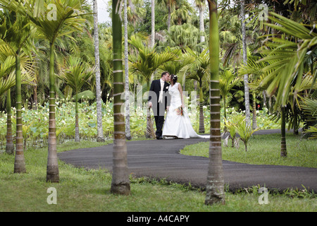 Mariée et le marié marcher dans un jardin tropical Banque D'Images