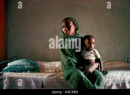 Femme tenant un enfant assis sur le lit au cours de la famine au Soudan 1991 Banque D'Images