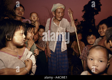 Birmanie 1992 : 2 500 personnes déplacées Karen : Une vieille femme appuyée sur stick parle à une foule d'enfants. Banque D'Images