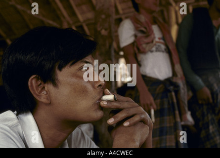 Birmanie frontière thaïlandaise, 1992 : Après les attaques de l'armée birmane des milliers de réfugiés ont franchi Mon Karen en Thaïlande. Un homme fume. Banque D'Images