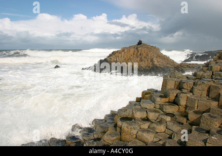 Royaume-uni le comté d'Antrim Giants Causeway couple assis sur des rochers avec des vagues se brisant autour Banque D'Images