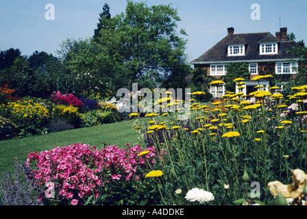 Long View de grande maison de campagne montrant pelouse et vivaces d'été rose phlox et frontières avec l'Achillea jaune Banque D'Images