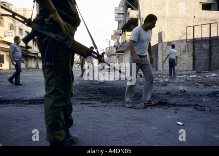 Des soldats israéliens pour les Palestiniens d'éteindre un incendie pneu après demos 1988 Banque D'Images