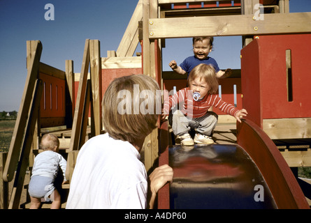Une assistante maternelle joue avec les tout-petits sur une diapositive dans une aire de jeux en plein air. Arhus, Danemark Banque D'Images
