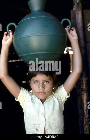 El Salvador .Jeune fille portant un pot d'eau en plastique vert sur sa tête . Banque D'Images