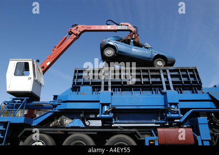 Une voiture abandonnée est chargé dans un broyeur avant d'être écrasé à une casse. Banque D'Images