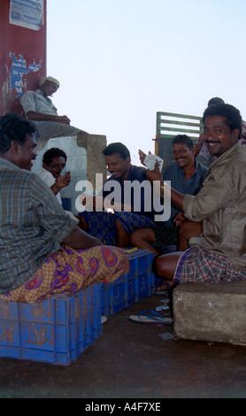 Les pêcheurs se détendre avec un jeu de cartes à un marché de poisson de Kerala, Inde Banque D'Images