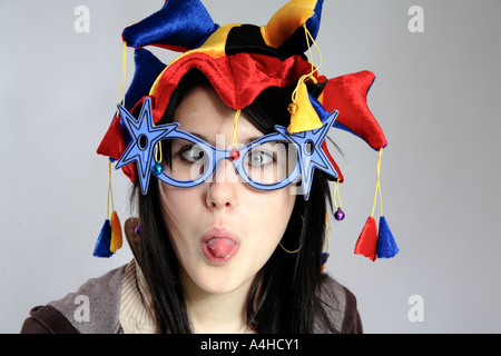 Jeune femme avec chapeau jesters et lunettes nouveauté tire sa langue, Banque D'Images