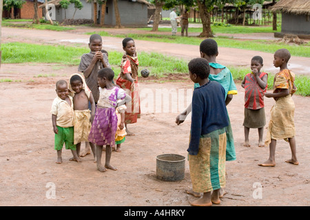 Enfants jouant un jeu impliquant une balle, une et quelques bâtonnets dans le village d'Khoswe, Malawi, Afrique Banque D'Images