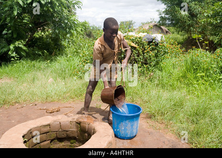 Garçon dimensions de l'eau d'un puits dans le village de Mambala, Malawi, Afrique Banque D'Images