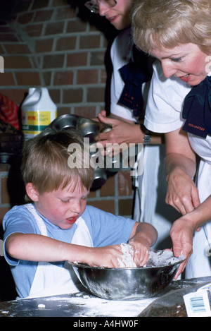 Jeune garçon enfant pâte à pétrir dans un bol et faire un gâchis de la farine dans la cuisine tout en apprenant à cuire Banque D'Images