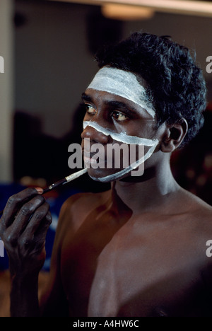 Un aborigène australien peignant son visage dans les coulisses de la préparation d'une performance sur scène Banque D'Images
