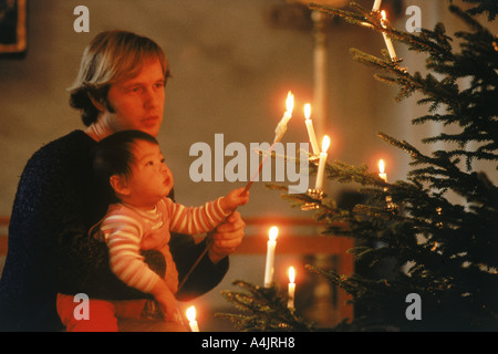 Papa avec enfant allumant des bougies sur l'arbre de Noël de la famille Banque D'Images