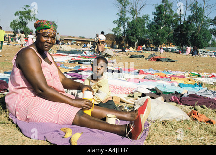 Femme africaine et de l'enfant aux côtés de la seconde main vêtements qu'elle vend le canton de Soweto, Johannesburg Afrique du Sud Banque D'Images