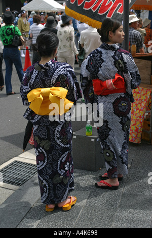 Deux jeunes femmes en tenue d'été traditionnels japonais kimonos Yukata regarder l'ancien festival de Gion Matsuri à Kyoto au Japon Banque D'Images