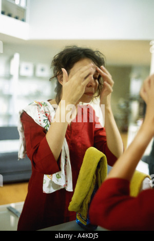 Woman touching forehead in front of mirror Banque D'Images