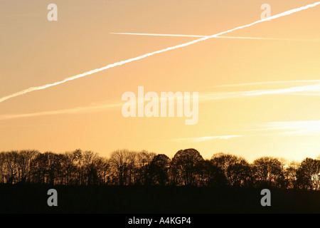 Des traînées de vapeur dans le ciel au coucher du soleil Banque D'Images