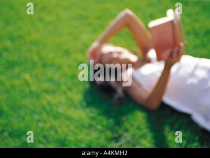 Woman lying on grass, lecture, defocused Banque D'Images