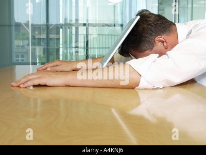 Businessman lying with face on laptop Banque D'Images