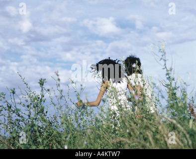 Vue arrière du jeune homme et la jeune femme à travers l'herbe haute Banque D'Images