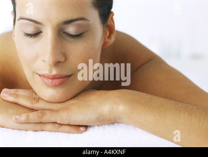 Femme couchée avec menton reposant sur les mains, les yeux clos, close-up Banque D'Images