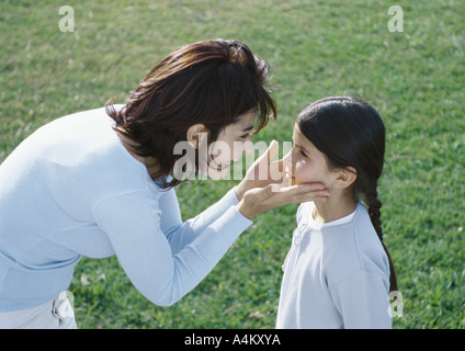 Femme se tenant face filles entre les mains, side view Banque D'Images