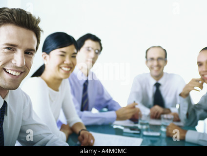 Businesspeople sitting around table, smiling Banque D'Images