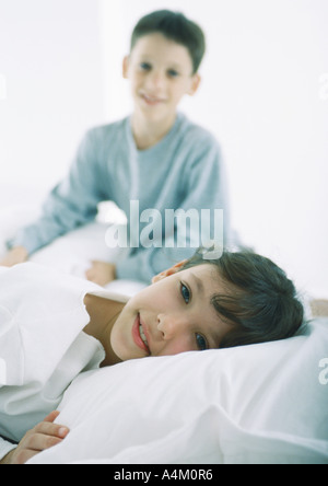 Girl Lying in Bed looking at camera, garçon en arrière-plan Banque D'Images