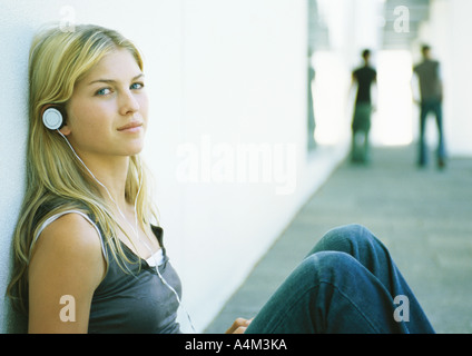 Young woman listening to headphones, looking at camera Banque D'Images