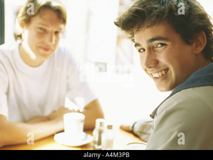 Deux jeunes hommes assis à table, smiling Banque D'Images