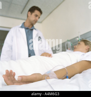 Médecin et female patient lying in hospital bed Banque D'Images